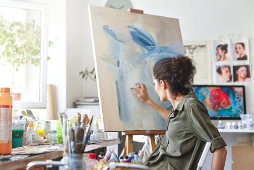 mulher pintando tela abstrata em azul