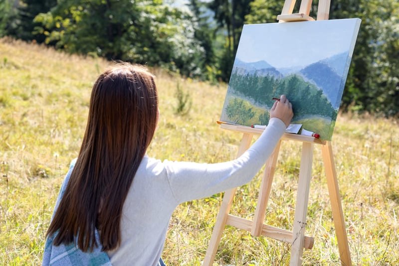 Mulher pintando paisagem de montanhas