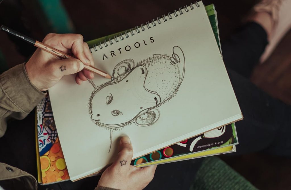 Artista desenhando em caderno com lápis graduado da Artools